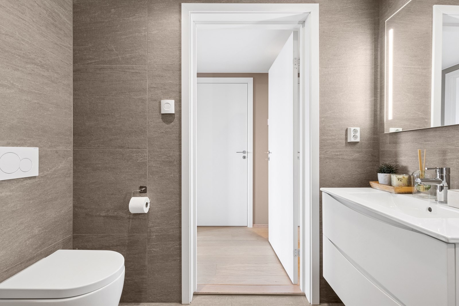 Baderomsinnredning med 2 skuffer og nedfelt servant med overhengende speil med belysning. Galleribilde