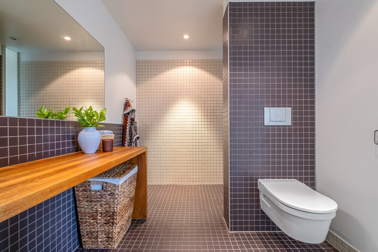 Baderommet er innredet med vegghengt klosett, servant nedfelt i innredning og dusjnisje. Galleribilde