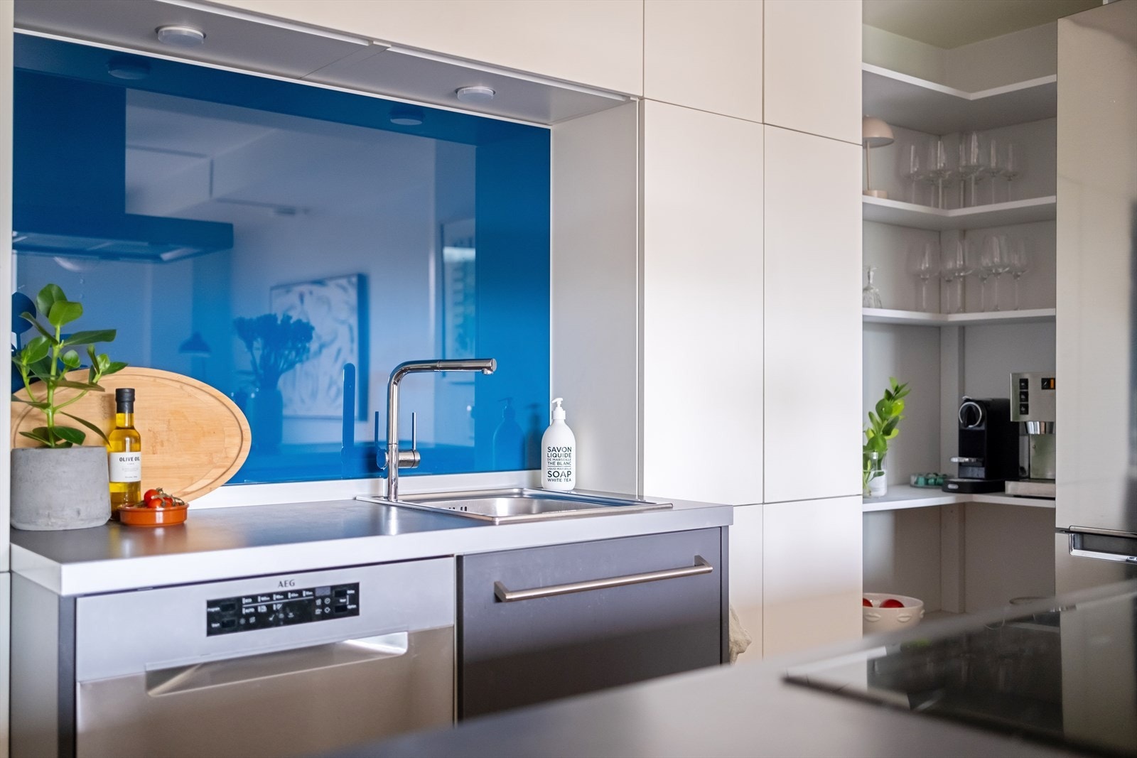 Kjøkkeninnredning med glatte fronter, laminat benkeplate med nedfelt vaskekum og glassplate over deler av benkeplaten. Galleribilde