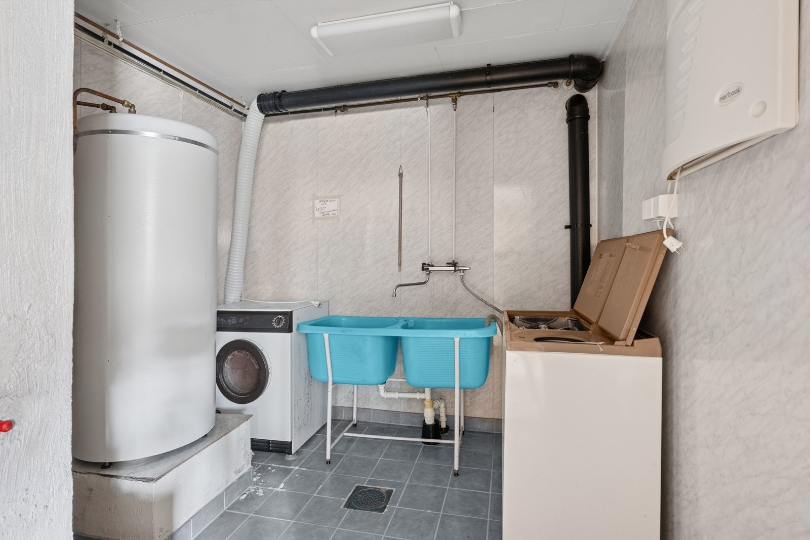 Vaskerom innredet med utslagsvask, varmtvannsbereder og opplegg for vaskemaskin. Galleribilde
