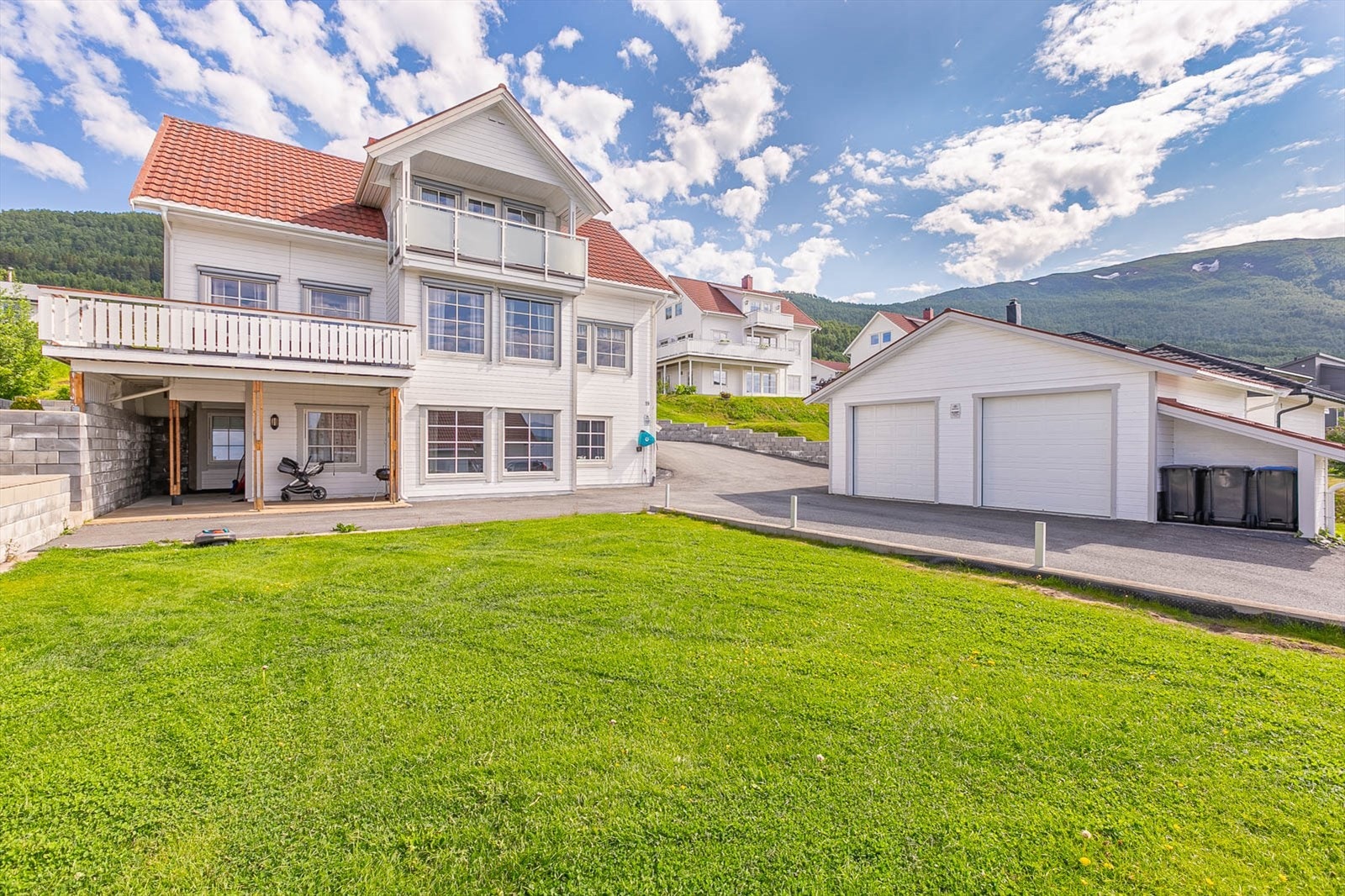 Meget pent opparbeidet tomt med plen og asfalt rundt huset og garasjen. Galleribilde