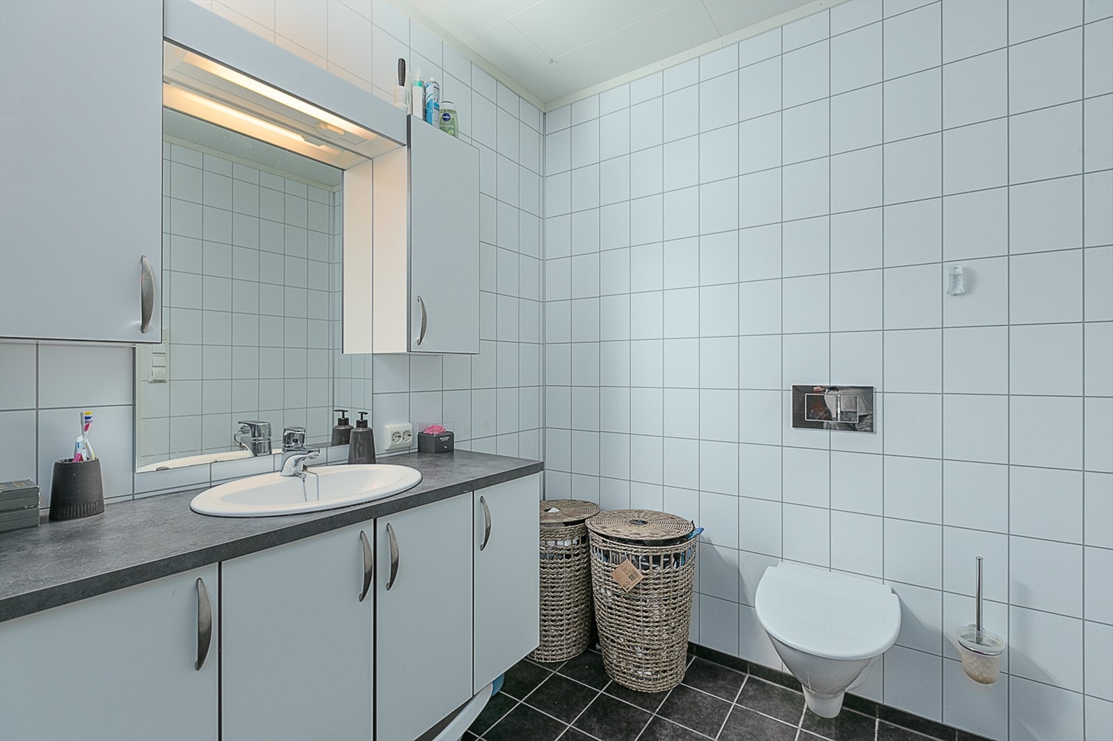 Bad med baderomsinnredning og vegghengt toalett. Galleribilde