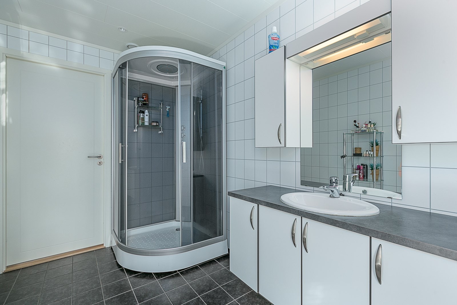 Baderomsinnredning med servant og innredning og dusjkabinett i hjørnet. Galleribilde