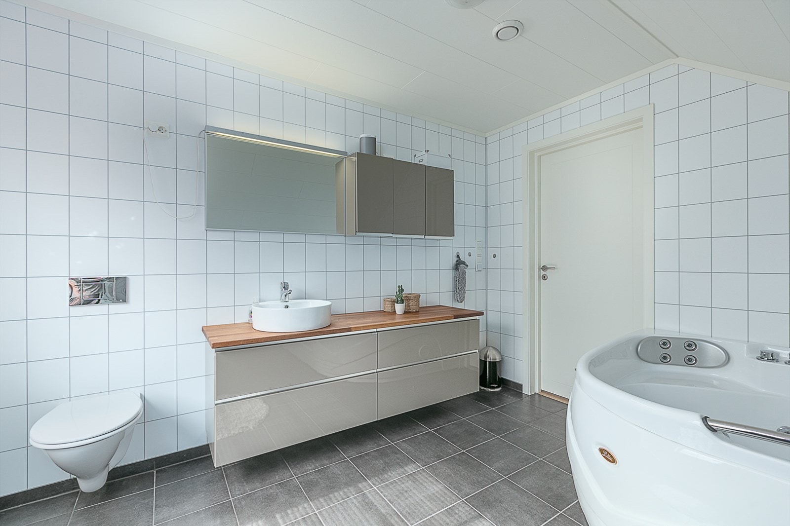 Stort bad med boblebadekar og vegghengt toalett. Galleribilde