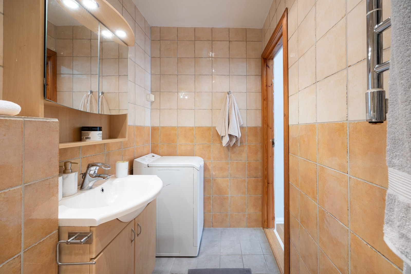 Flislagt bad med servantskap og opplegg for vaskemaskin. Galleribilde