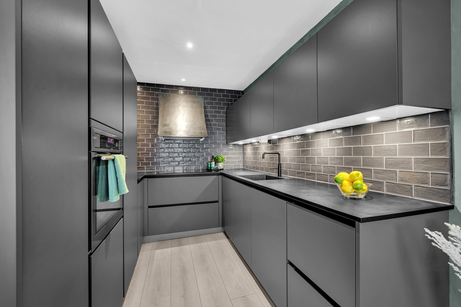 Kjøkkenet fremstår stilrent med mørke, slette fronter. Galleribilde