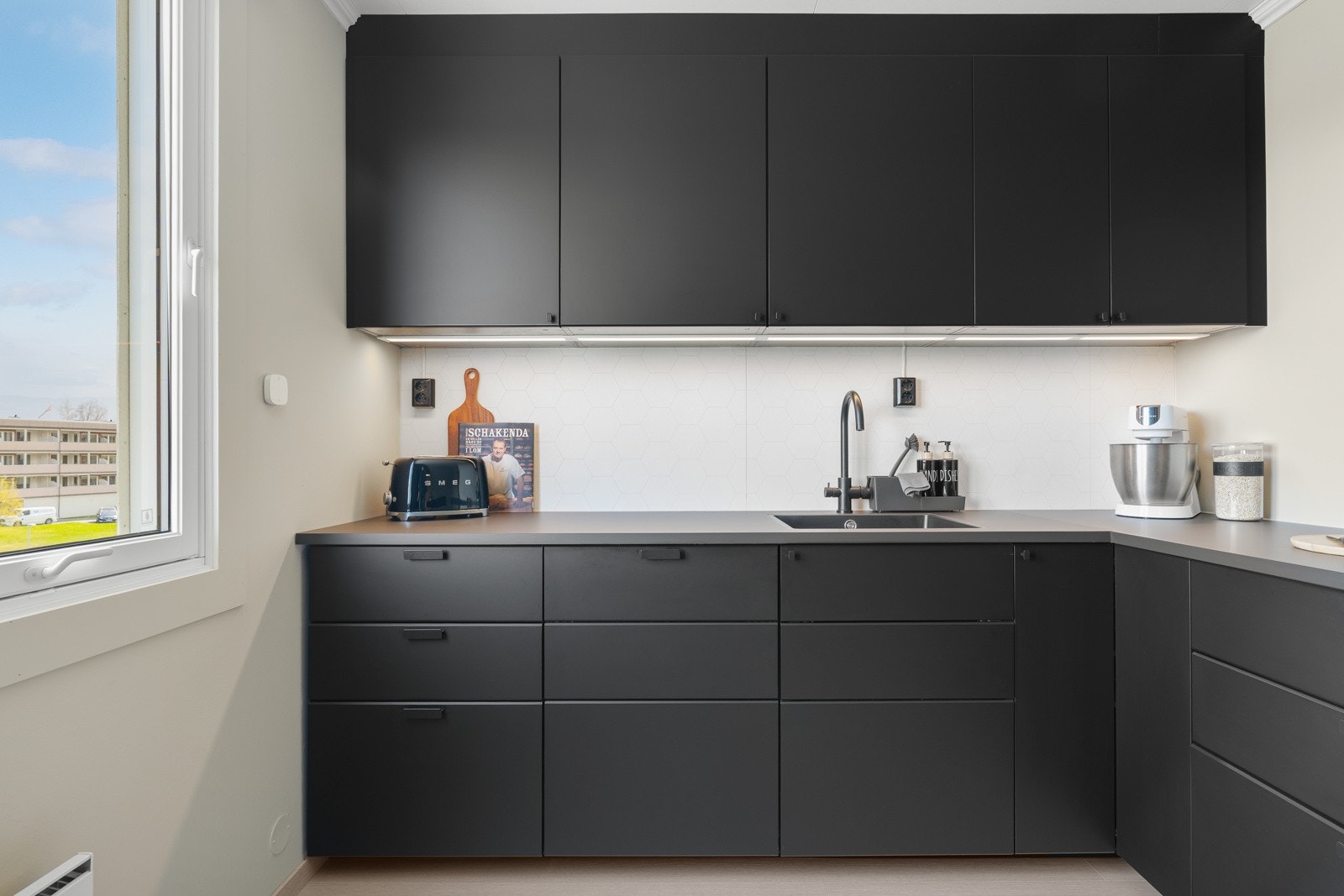 Kjøkkenet har et moderne uttrykk som harmonerer fint med boligens helhetlige stil. Downlights i himling og store vindusflater sørger for god belysning. Galleribilde