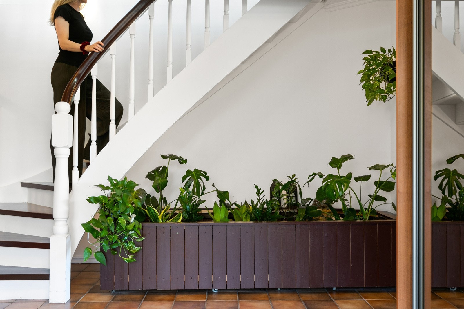 Hall hvor trappen opp til andre etasje er plasert over en liten grønn oase. Galleribilde