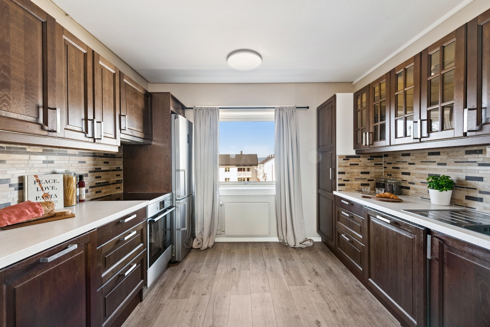 Innredning i heltre med profilerte fronter og vitrinedører. Laminat benkeplate og fliser over benk Galleribilde