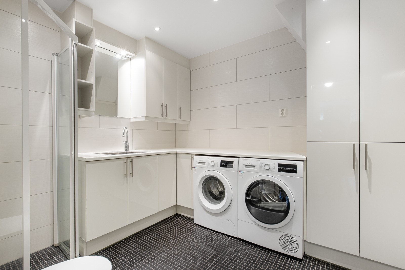 Bad/vaskerom i kjelleretasjen med praktisk innredning - flislagt med varmekabler, dusjnisje og wc. Galleribilde