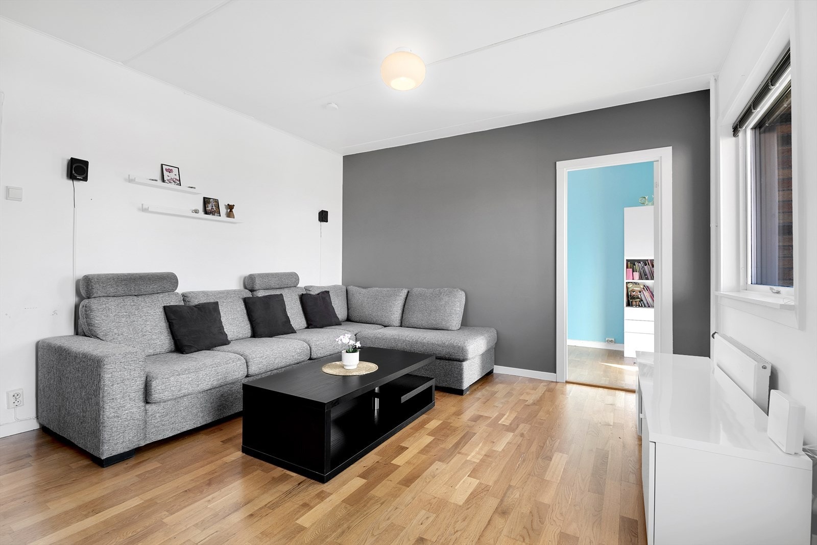 Stuen er lys og romslig med moderne fondvegg i grått. Her er det god plass til både sofagruppe og spisebord. Galleribilde