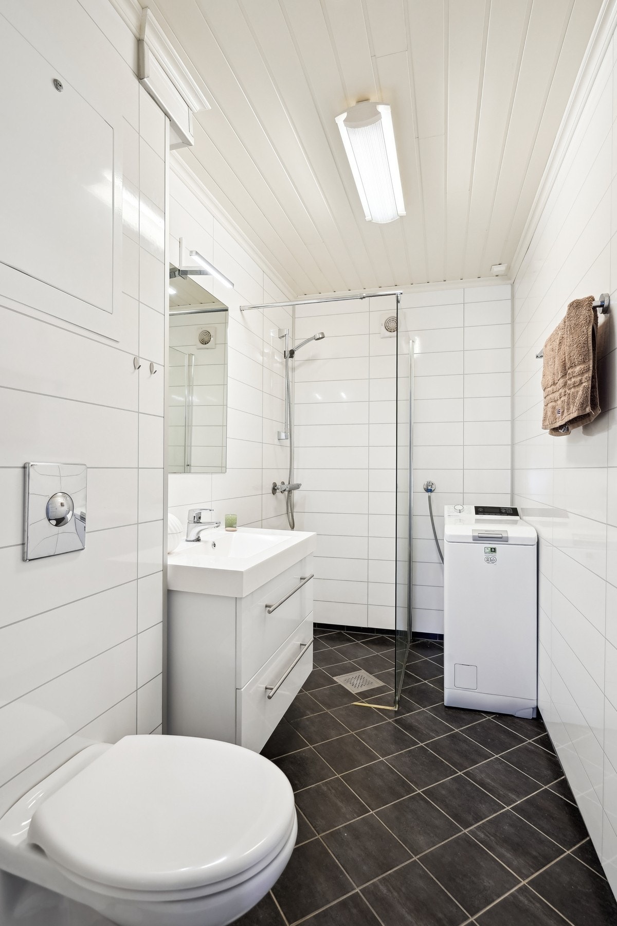 Flott bad med flislagt gulv og gulvvarme. Baderomsplater på veggene. Opplegg for vaskemaskin. Galleribilde