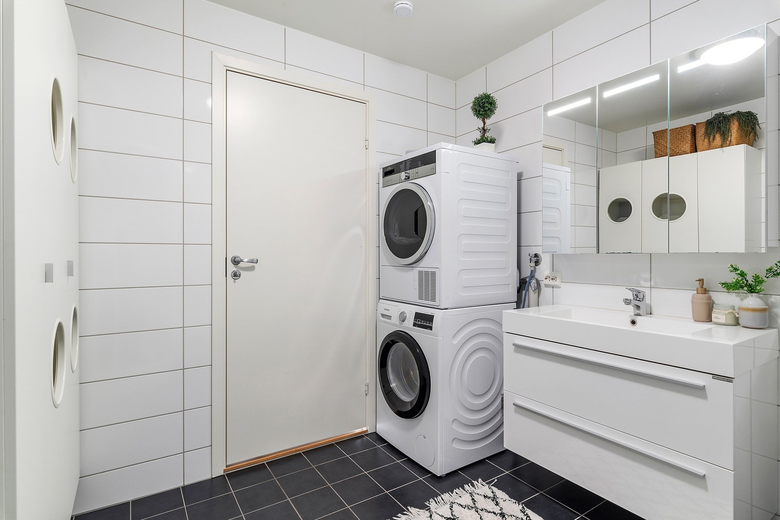 Det er opplegg for vaskemaskin og tørketrommel på badet, samt vegghengt baderomsmøbel for skittentøy Galleribilde