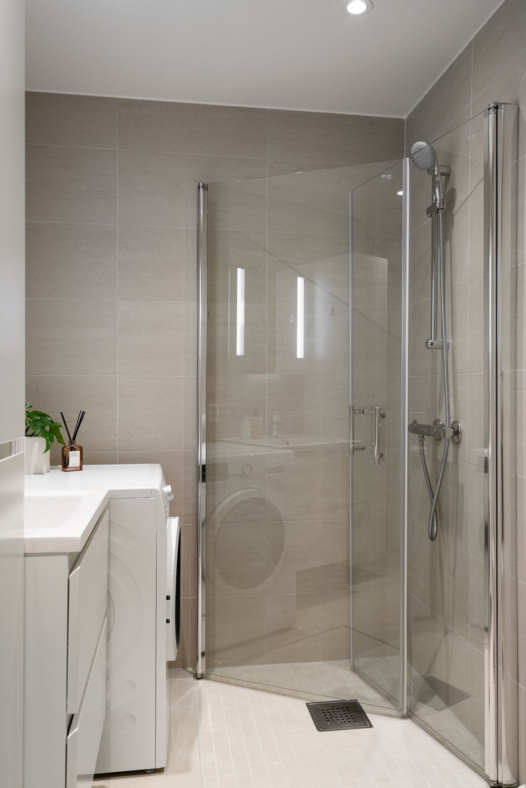 Badet har innsvingbare dusjdører, opplegg for vaskemaskin, wc og baderomsinnredning Galleribilde