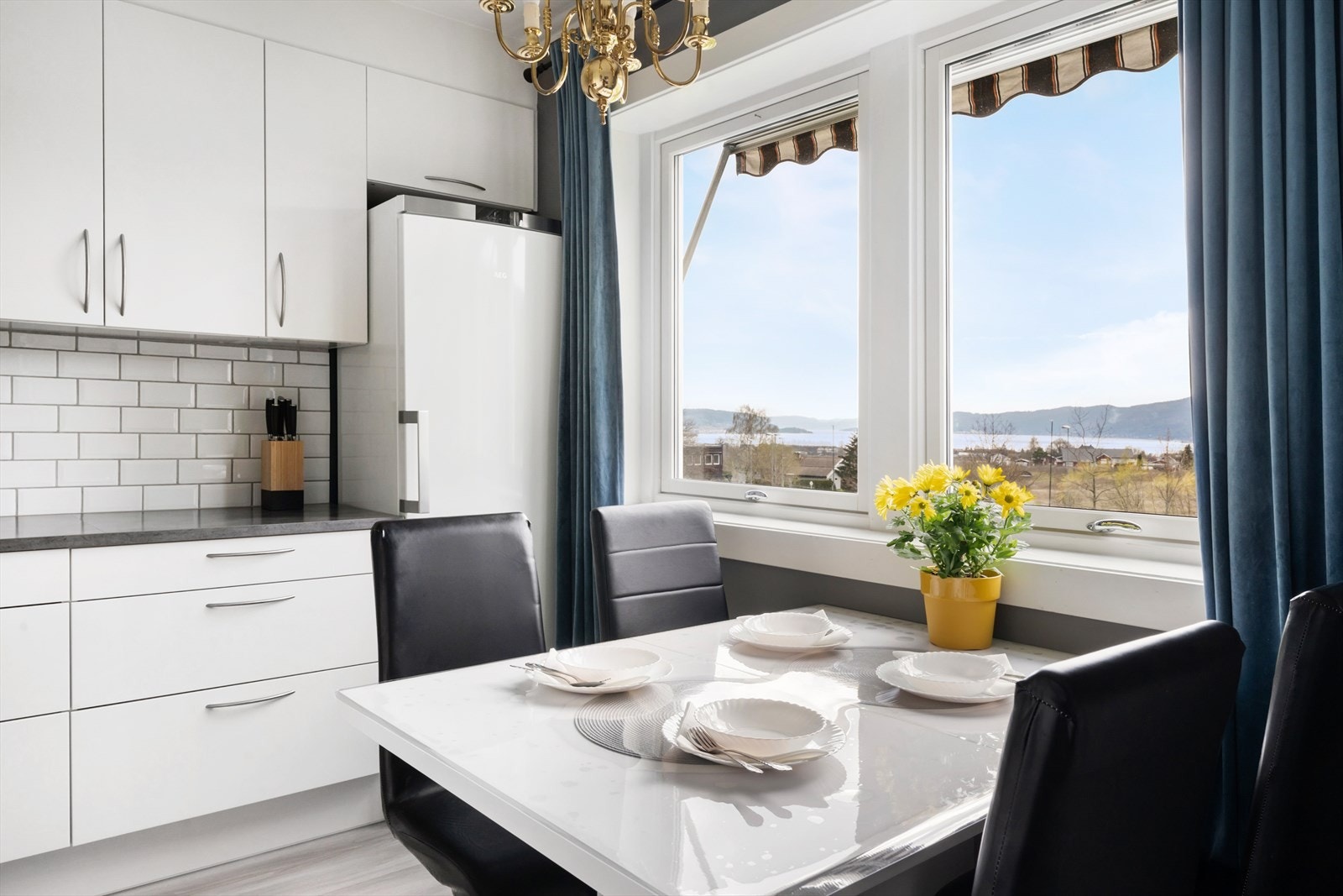 Klassisk kjøkkeninnredning som ligger adskilt fra stuen med slette, hvite fronter og benkeplate av laminat. Galleribilde