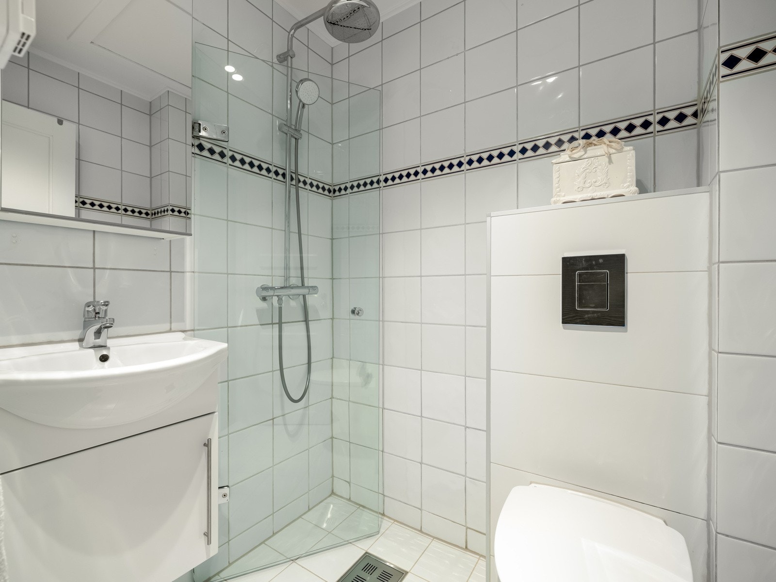 Badet er innredet med dusjhjørne, servant med skapinnredning og vegghengt toalett. Det er downlights i himling og, som nevnt, varmekabler i gulvet. Galleribilde