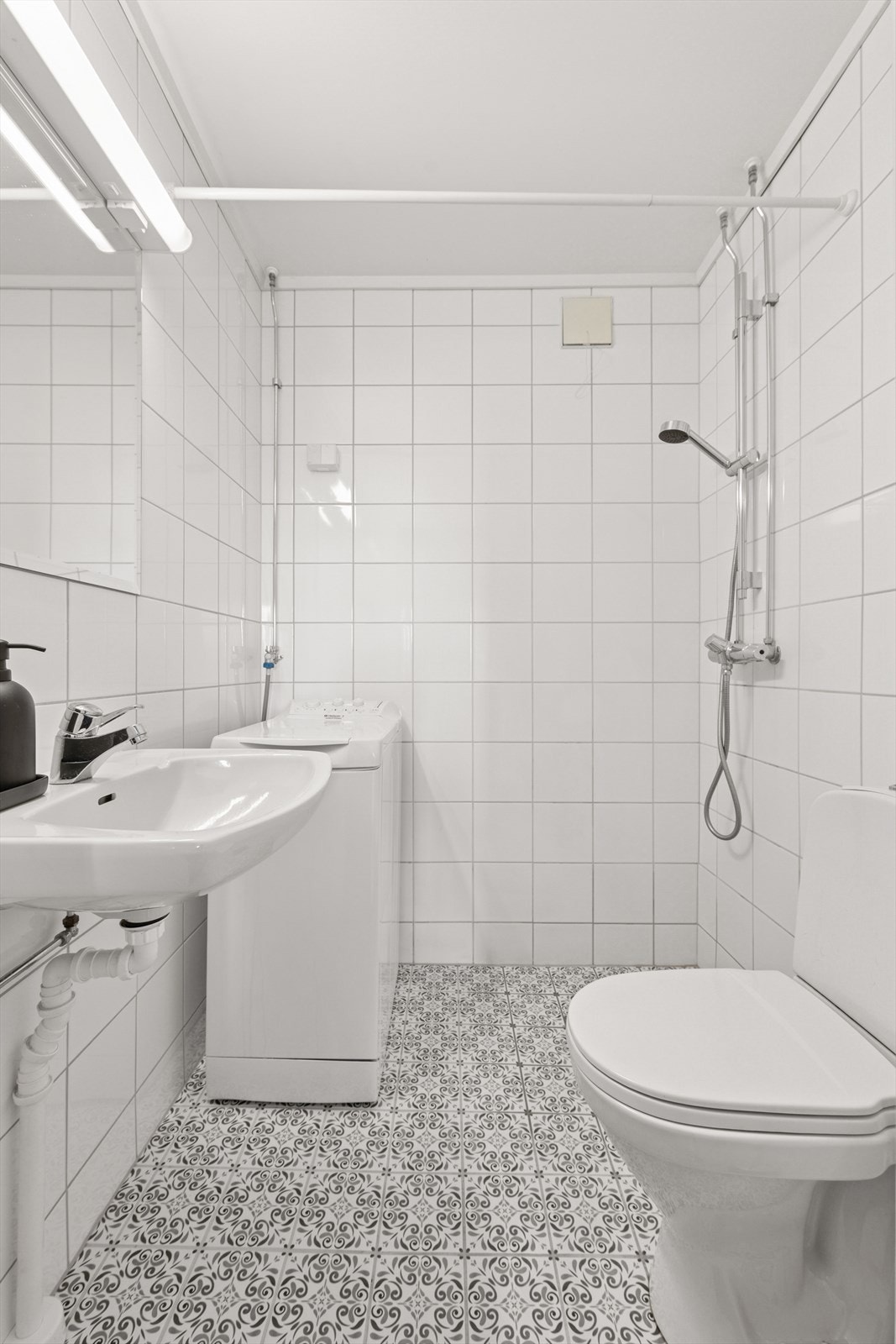 Badet har innredning som består av vegghengt servant, gulvmontert kloset, opplegg for vaskemaskin og dusjhjørne. Galleribilde