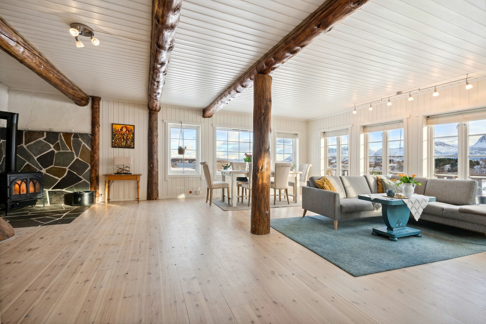 Lys og romslig stue med store vinduer, synlige tømmerbjelker og panoramautsikt. Galleribilde