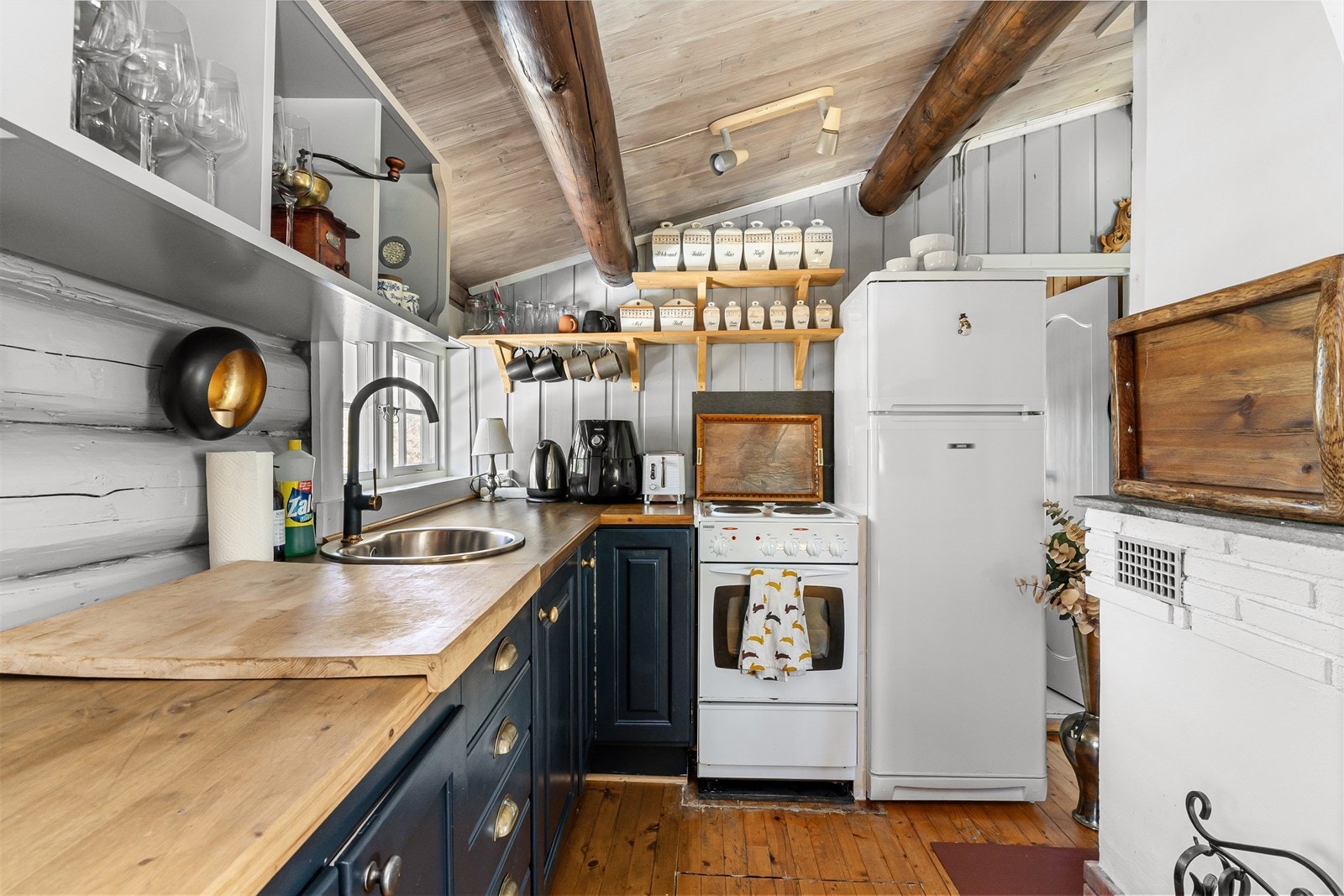 Hytta har et enkelt kjøkkenhjørne med innredning i vinkelløsning. Det er plassert en varmtvannsbereder i benkeskapet, og det er lagt vann til kjøkkenkrana fra et smart vannsystem selger har bygget selv. Galleribilde