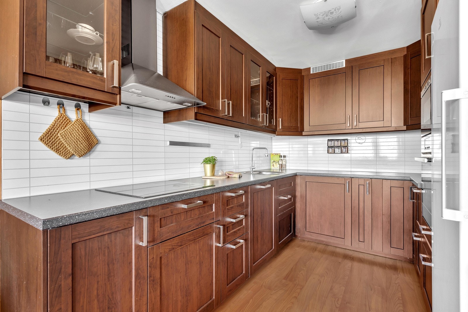 Kjøkkenet har mørke trefronter, hvite fliser og benkeplate i grå stein Galleribilde