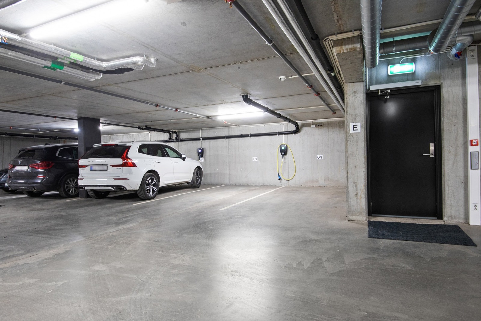 Det medfølger to biloppstillingsplasser ved siden av hverandre i garasjeanlegget, og det er montert el-bil lader midt mellom disse. Galleribilde