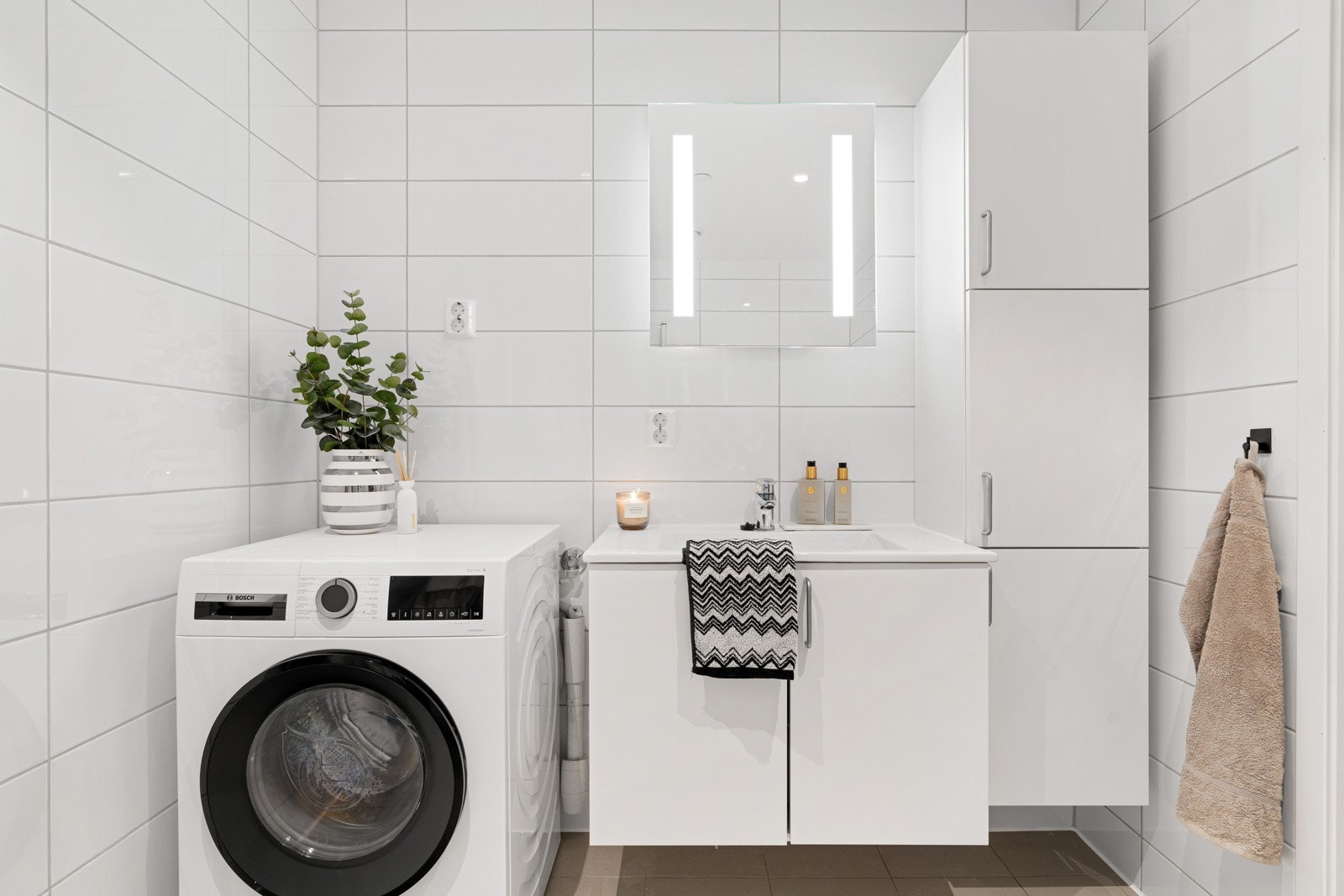 Her får man et stilrent baderom med lyse gulv- og veggfliser, et stilig felt med fliser i dusjsonen og downlights i himlingen. Galleribilde