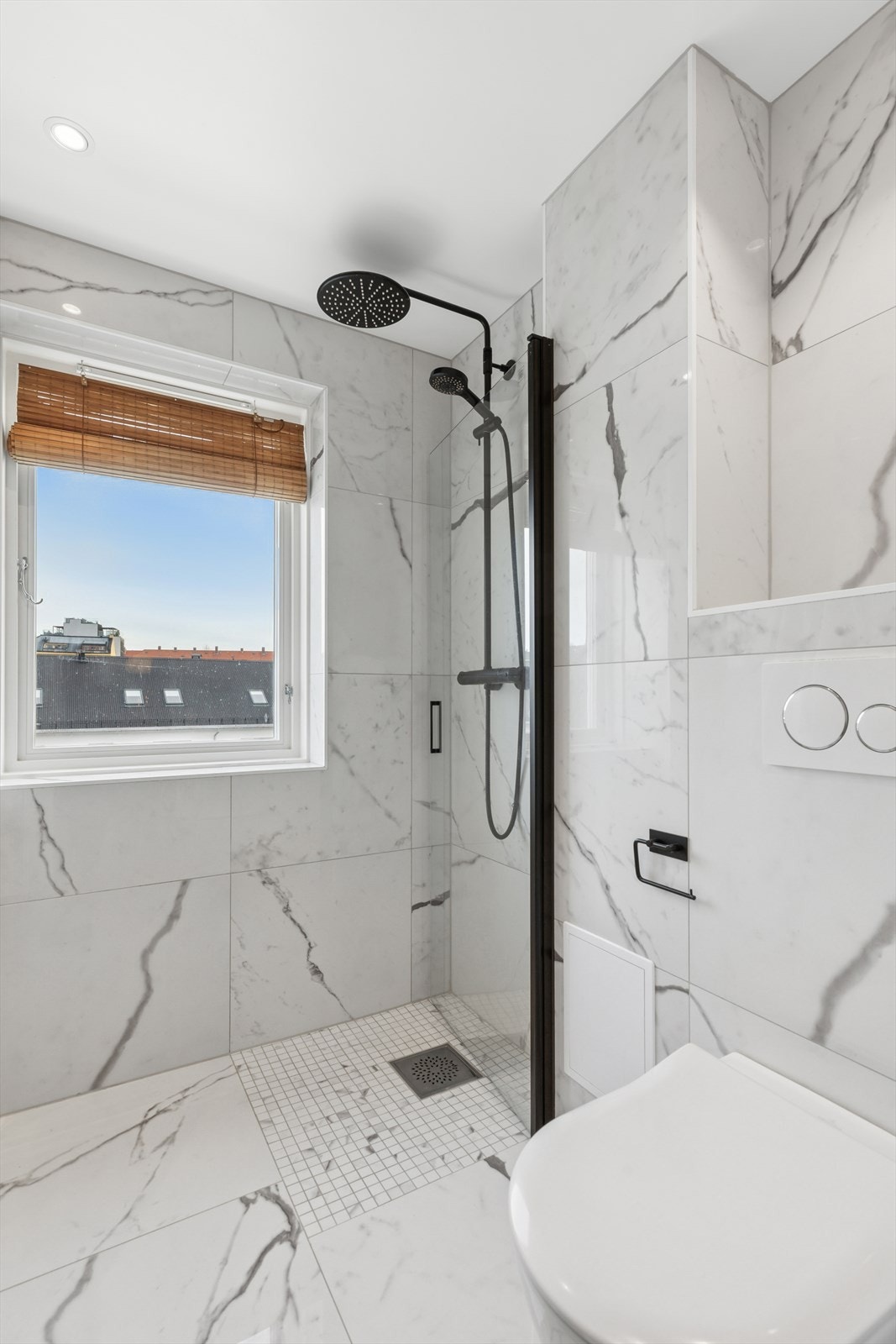 Baderommet fremstår svært delikat med lekre fliser i marmormønster på gulv og vegger. Det er varmekabler i gulvet og downlights i himlingen. Galleribilde