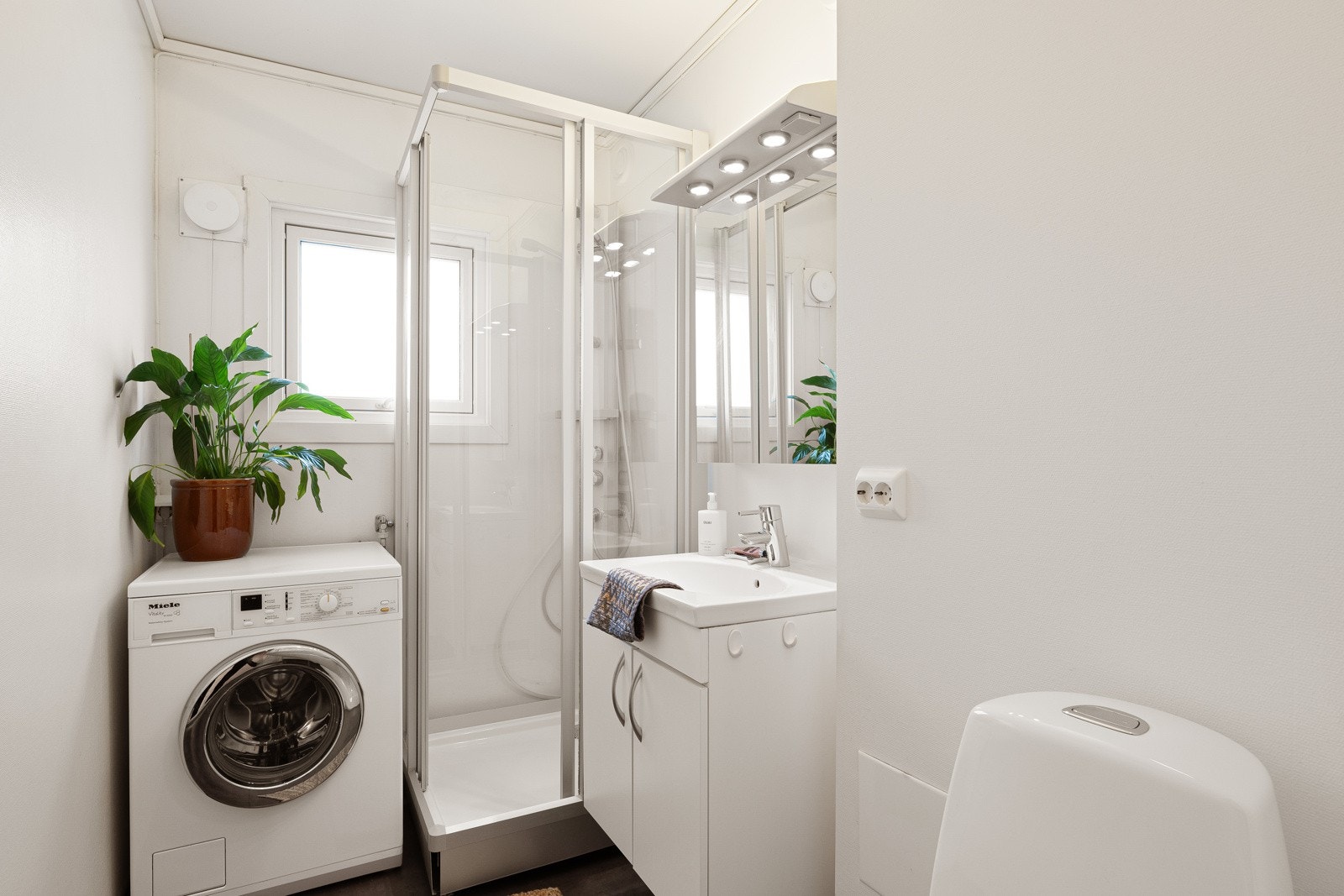 Badet er innredet med gulvbelegg og malte vegger og tak. Badet har servant, gulvmontert toalett, dusjkabinett og opplegg for vaskemaskin Galleribilde