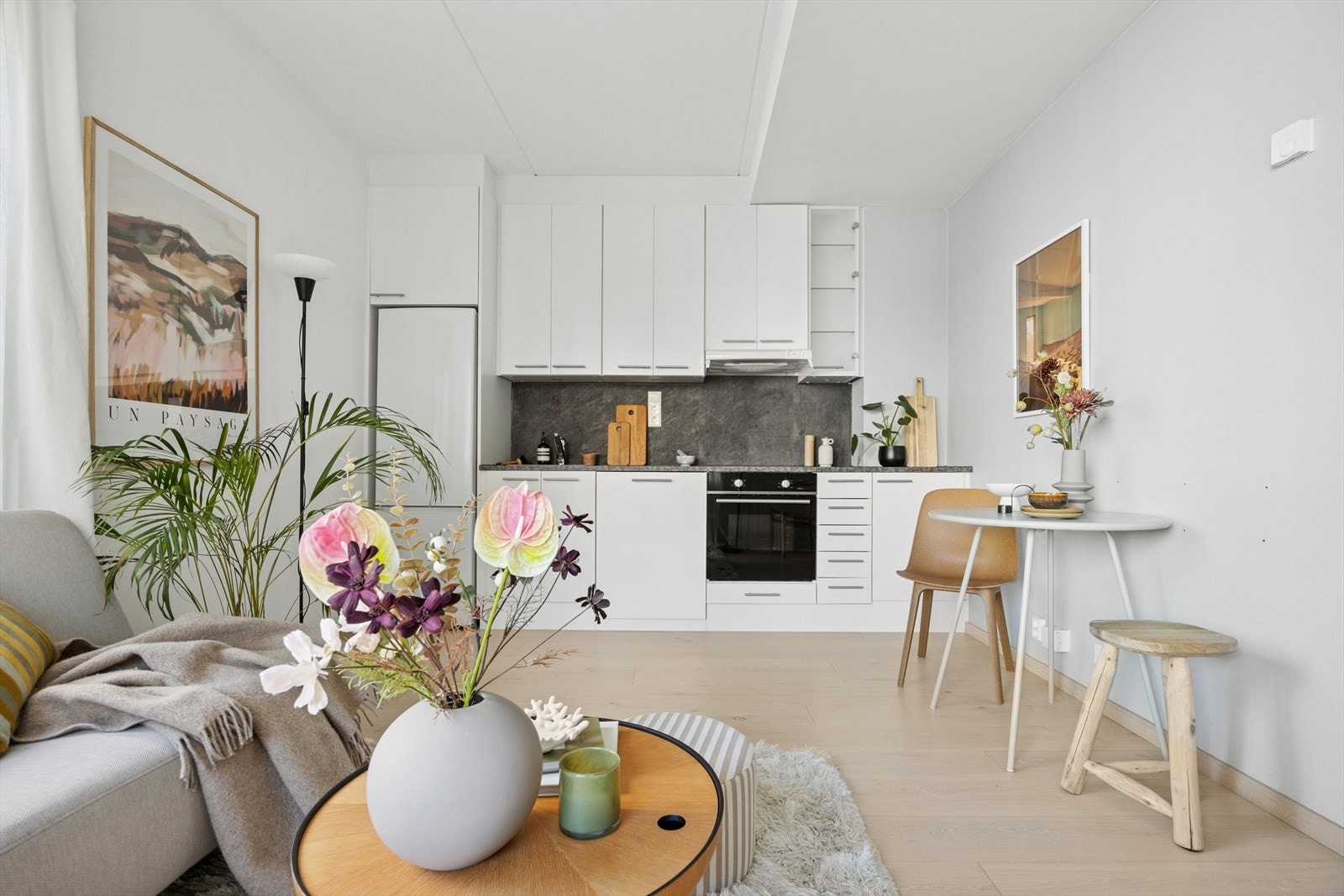 Kjøkkeninnredning med lyse slette fronter og integrerte hvitevarer som stekeovn, platetopp og oppvaskmaskin. Galleribilde