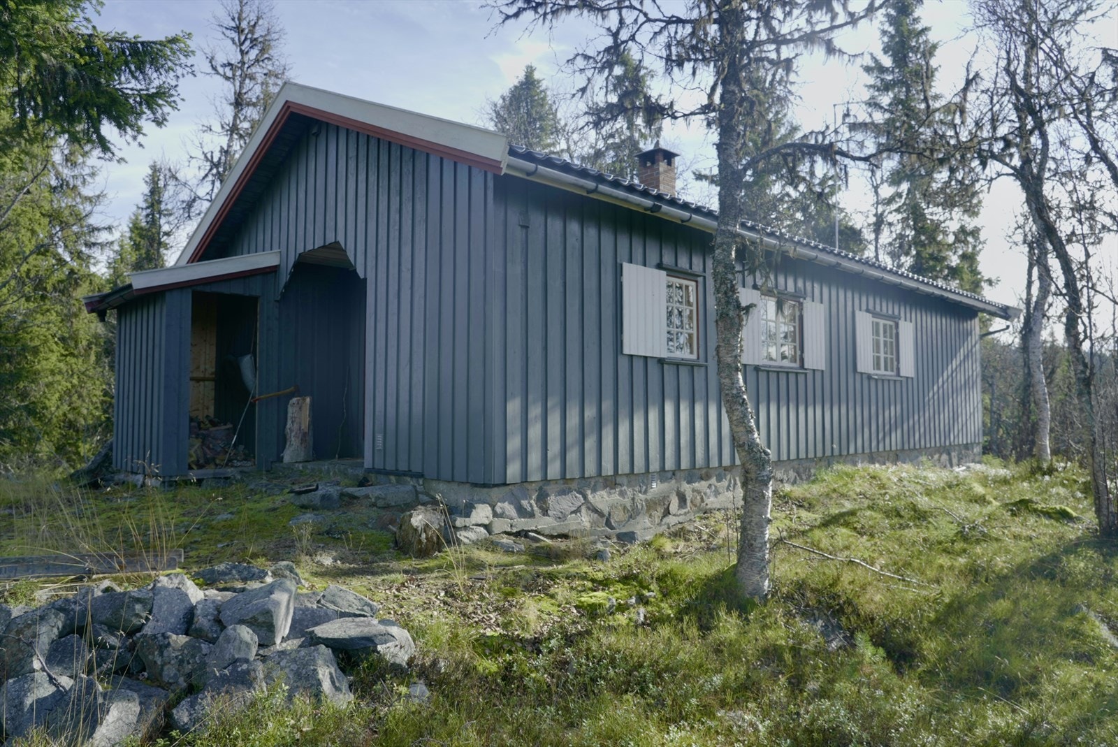 Hytta ligger på ca. 915 moh oppe på en kolle. Tomten er bevokst med gress, einer og bjerketrær. Galleribilde