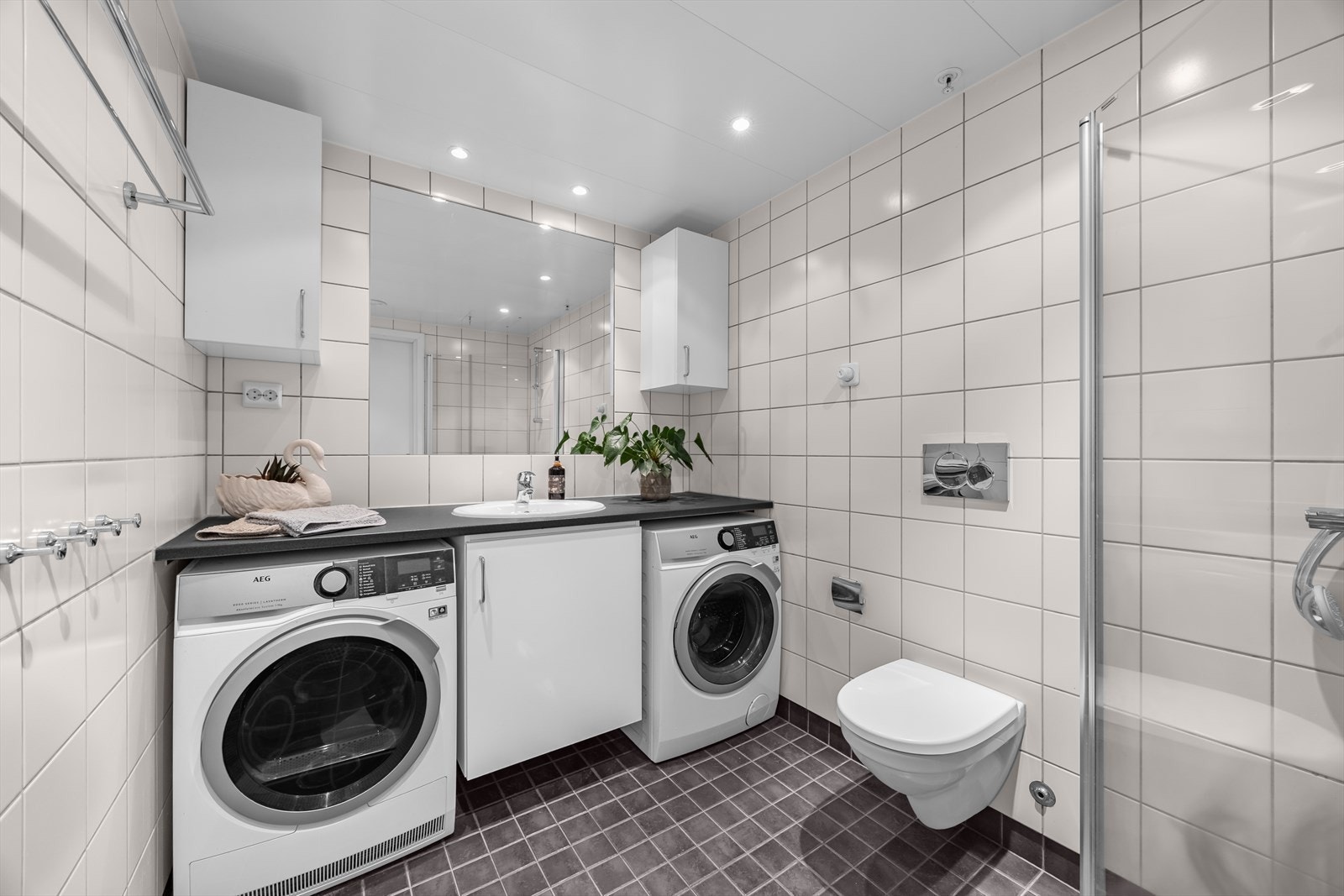Dette badet ligger i tilknytning til omkledningsrommet og hovedsoverommet. Badet er utstyrt med vegghengt toalett, dusjhjørne med dører i herdet glass, samt opplegg for vaskemaskin. Galleribilde