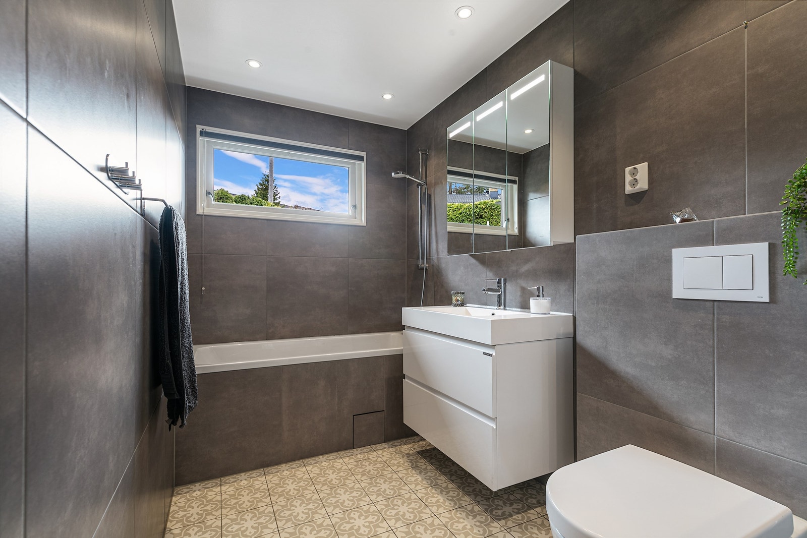 : Stilig og moderne bad med vegghengt toalett. Pusset opp i 2018. Lun varme i gulvet med varmekabler. Her kan en slappe av med et deilig bad i rommets badekar. Galleribilde