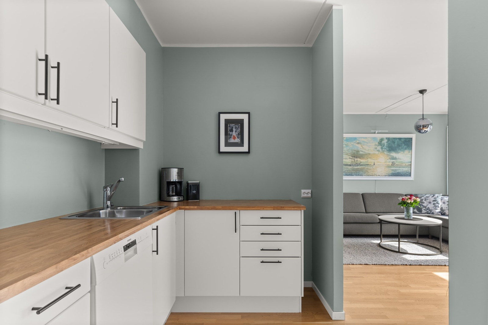 Kjøkkeninnredningen er av lyse, glatte fronter. Laminat benkeplate med nedfelt vask og avtrekk over kokeplass. Galleribilde