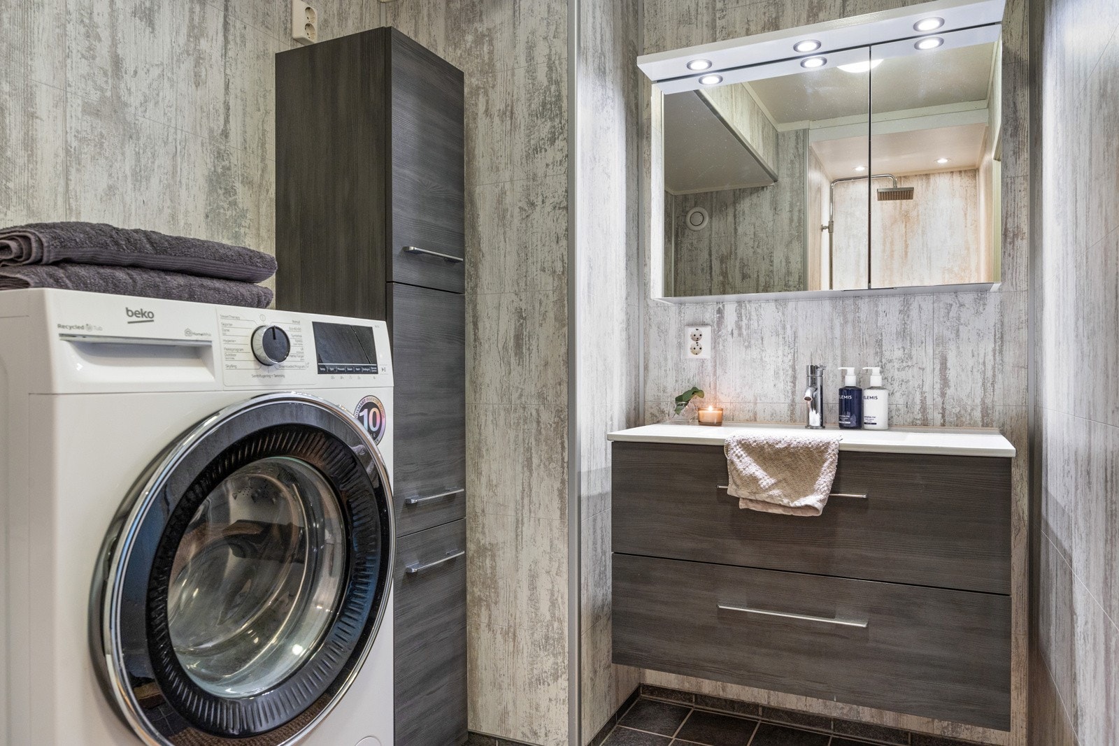 Det 4,5 kvm store badet er innredet med flislagt gulv og baderomsplater på veggene i betongutførelse. Baderomsinnredningen er delikat med nedfelt servant og skuffeseksjoner med god plass til toalettartikler. Galleribilde