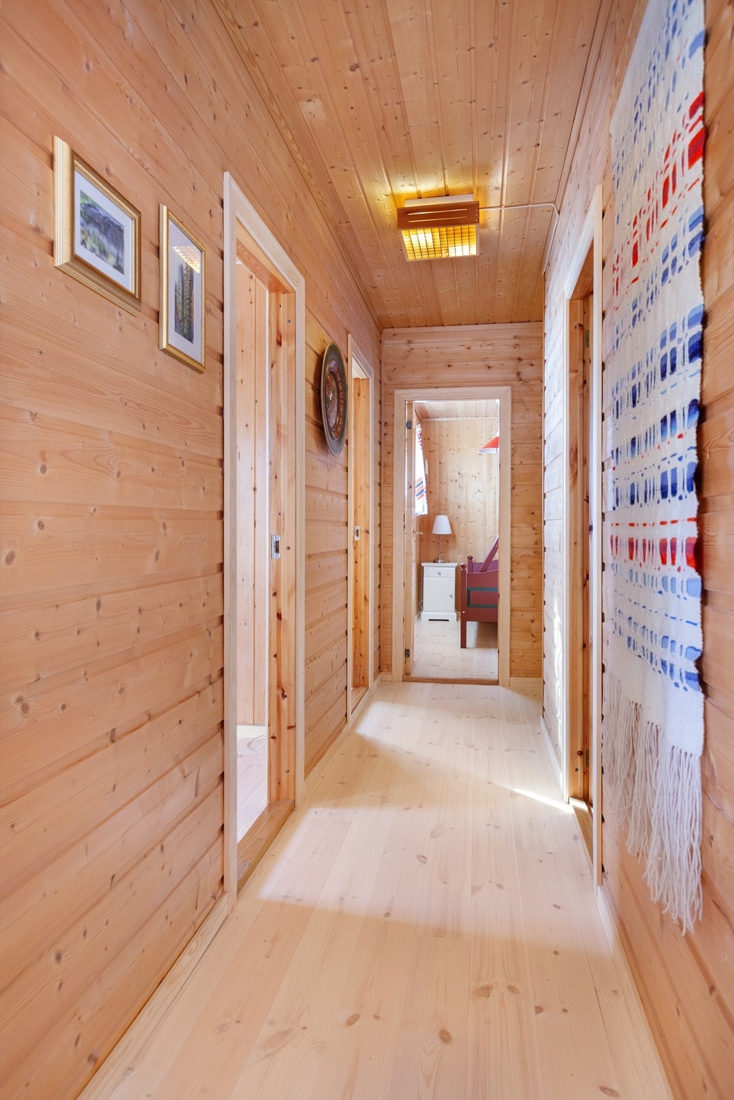 Lys og romslig gang med tregulv, panel på vegger og panel i tak. Galleribilde
