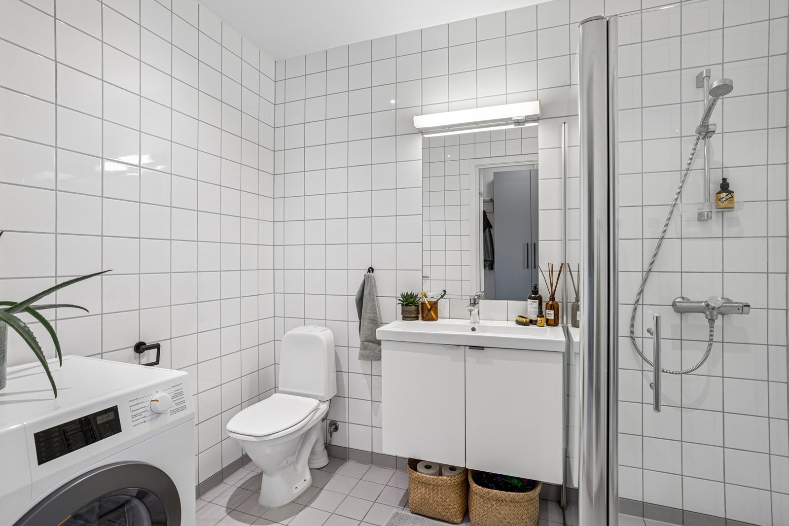 Flislagt baderom i tidløst uttrykk, som kombineres med vaskerom. Galleribilde