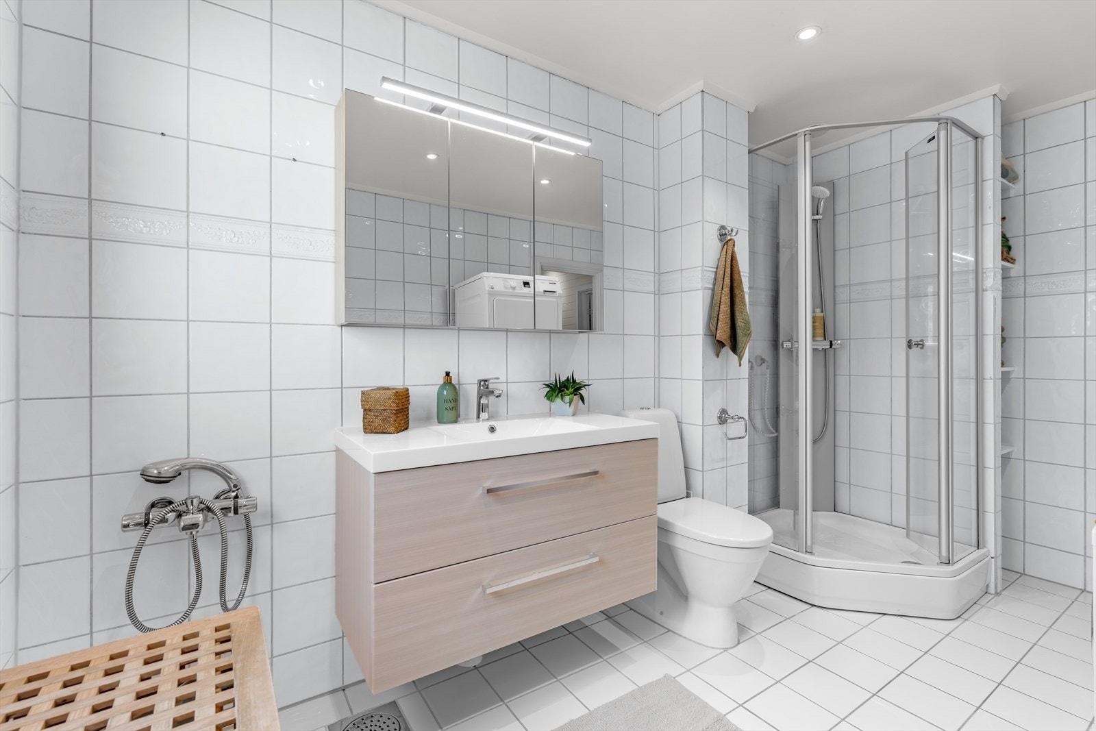 Baderommet er utstyrt med gulvstående klosett, dusjkabinett og servant i helstøpt plate med skuffeinnredning under. Galleribilde