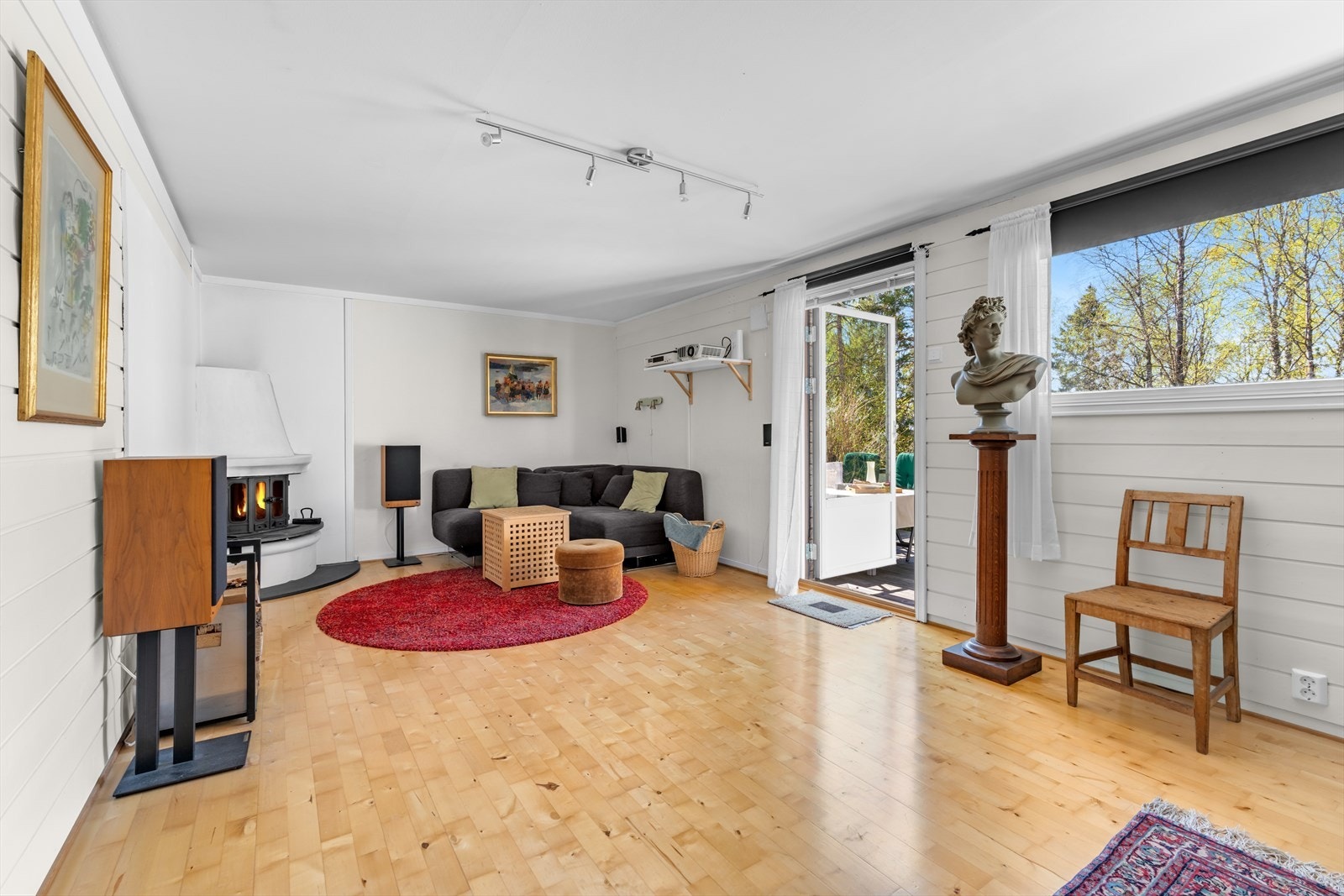 Stuen er utstyrt med en elementpeis med glatte hvite vanger, sokkel og kappe, samt innsats med glassdører. Galleribilde