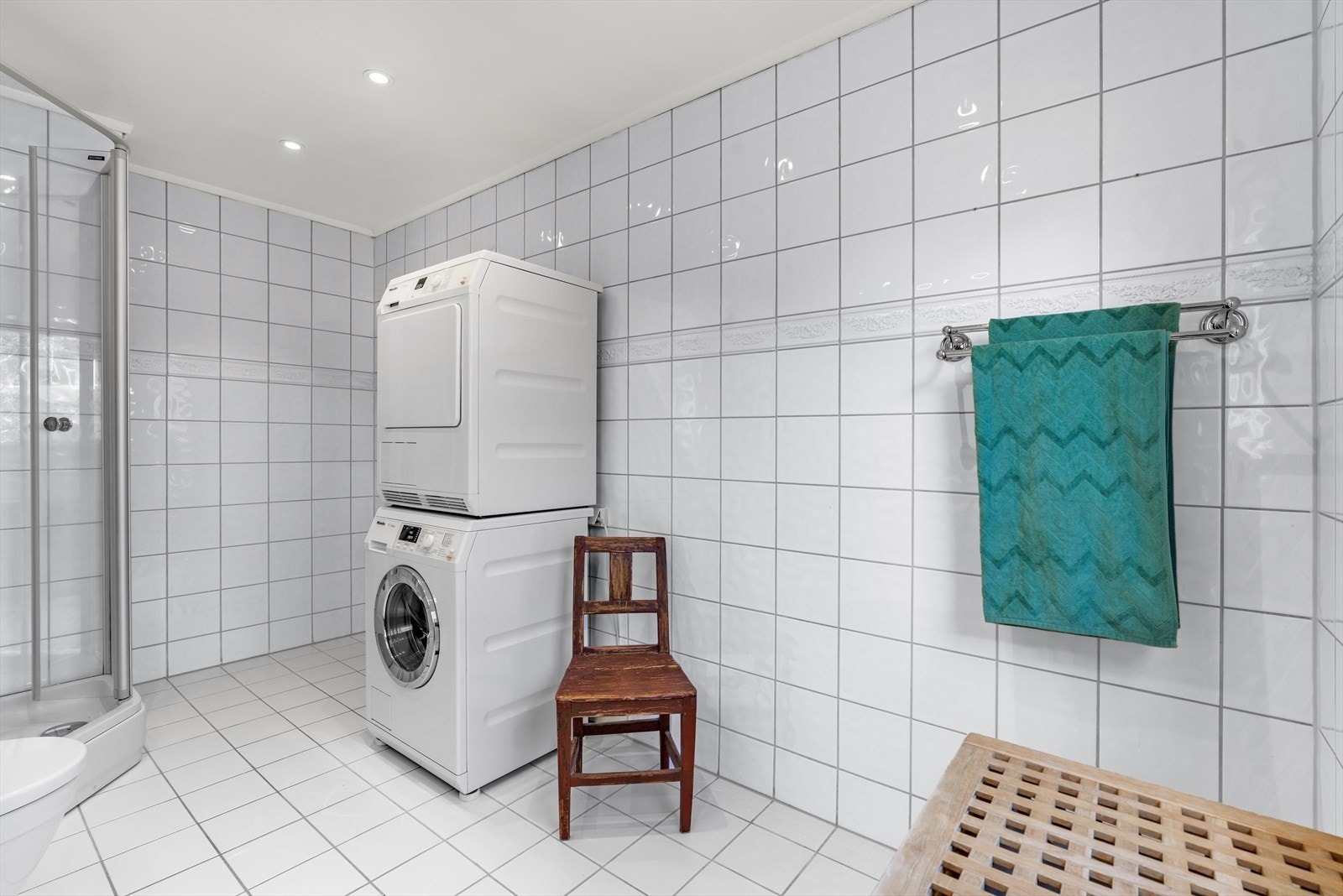 Badet har flislagte overflater på gulv og vegger, varmekabler i gulvet, innfelte lys i taket og opplegg for vaskemaskin. Galleribilde