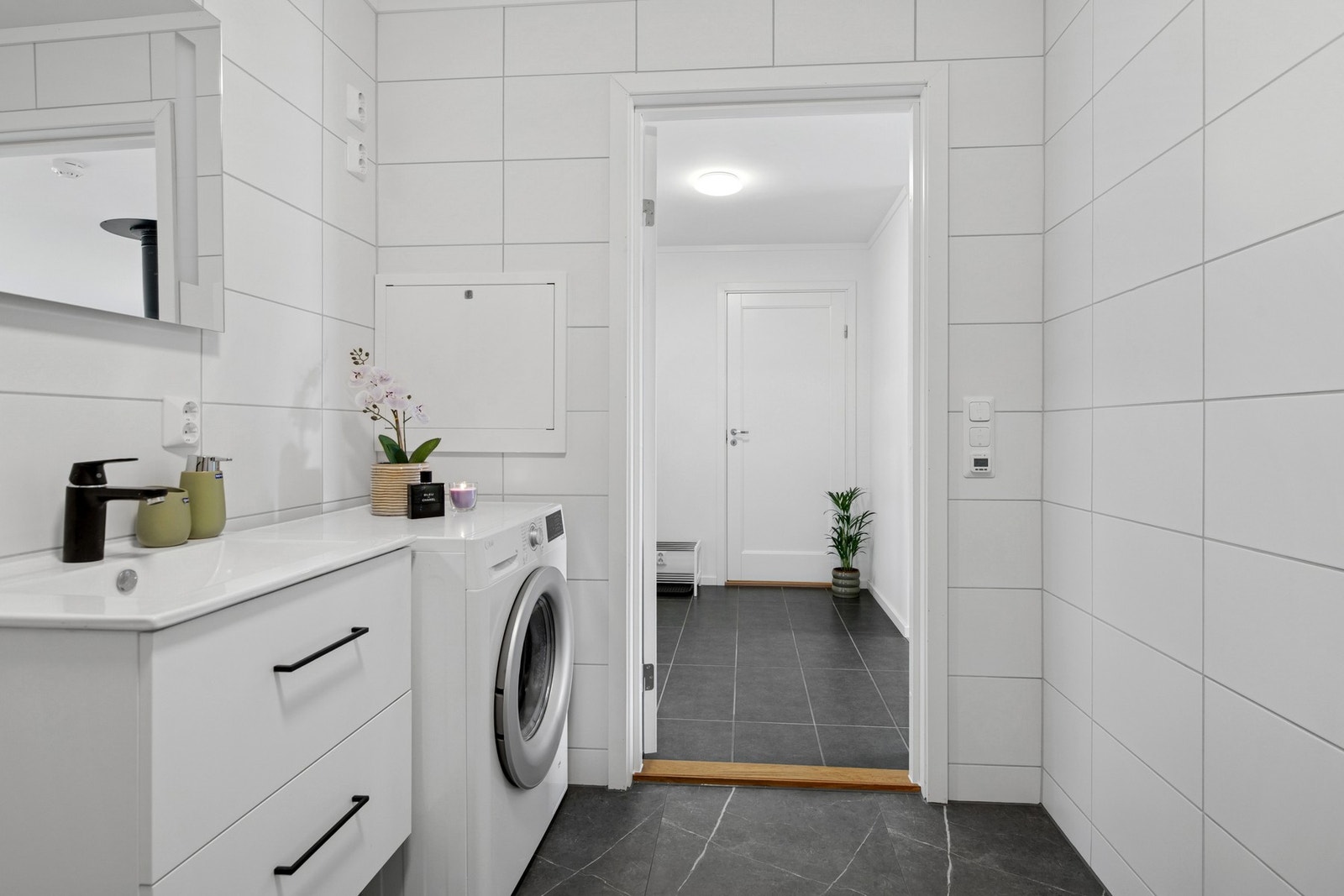 Det er elektrisk gulvvarme, vegghengt servantskap med heldekkende servant, speil med belysning, og en dusjnisje med regndusj og innfellbare glassdører. Opplegg for vaskemaskin. Galleribilde