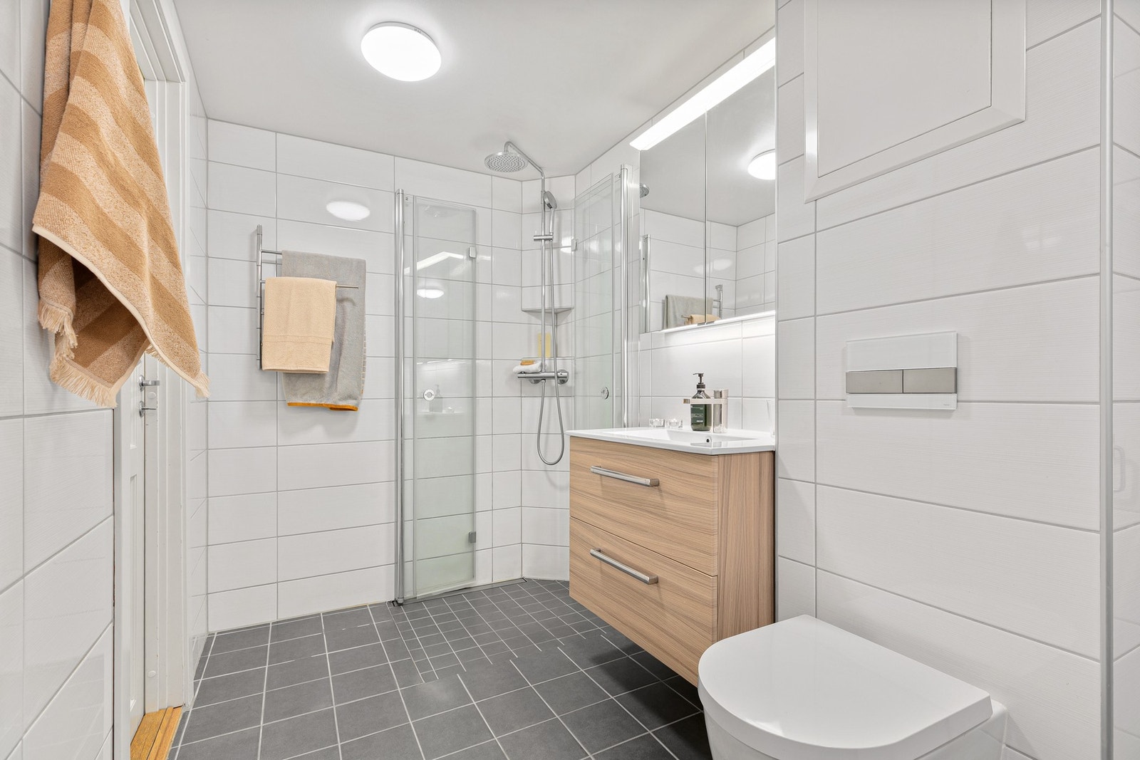 Badet er også innredet med vegghengt toalett, høyskap og heldekkende servant med skuffeseksjon Galleribilde