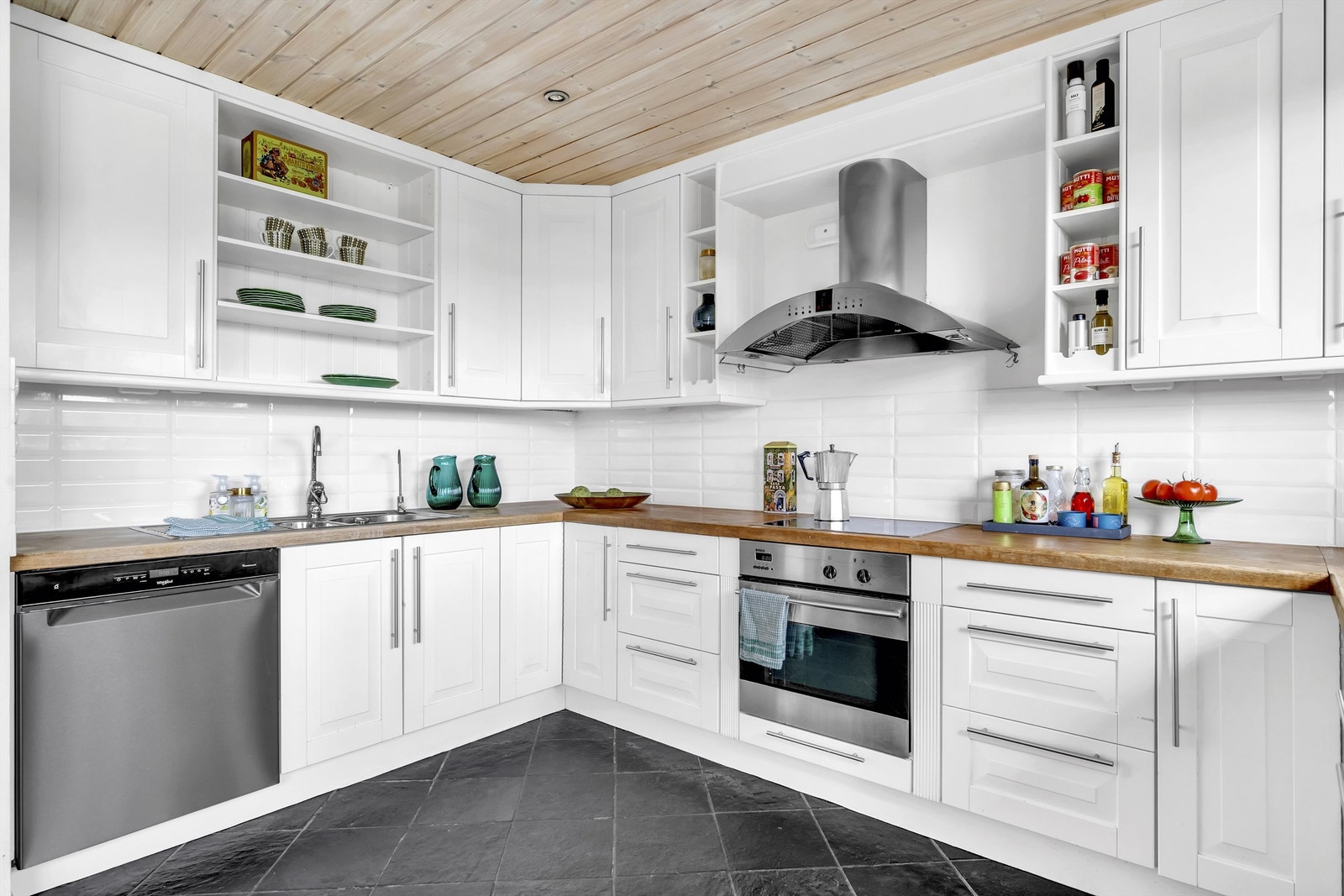 Kjøkkenet er innredet med kjøkkeninnredning med profilerte fronter, benkeplater av tre, nedfelt oppvaskkum, fliser mellom kjøkkenbenk og overskap Galleribilde