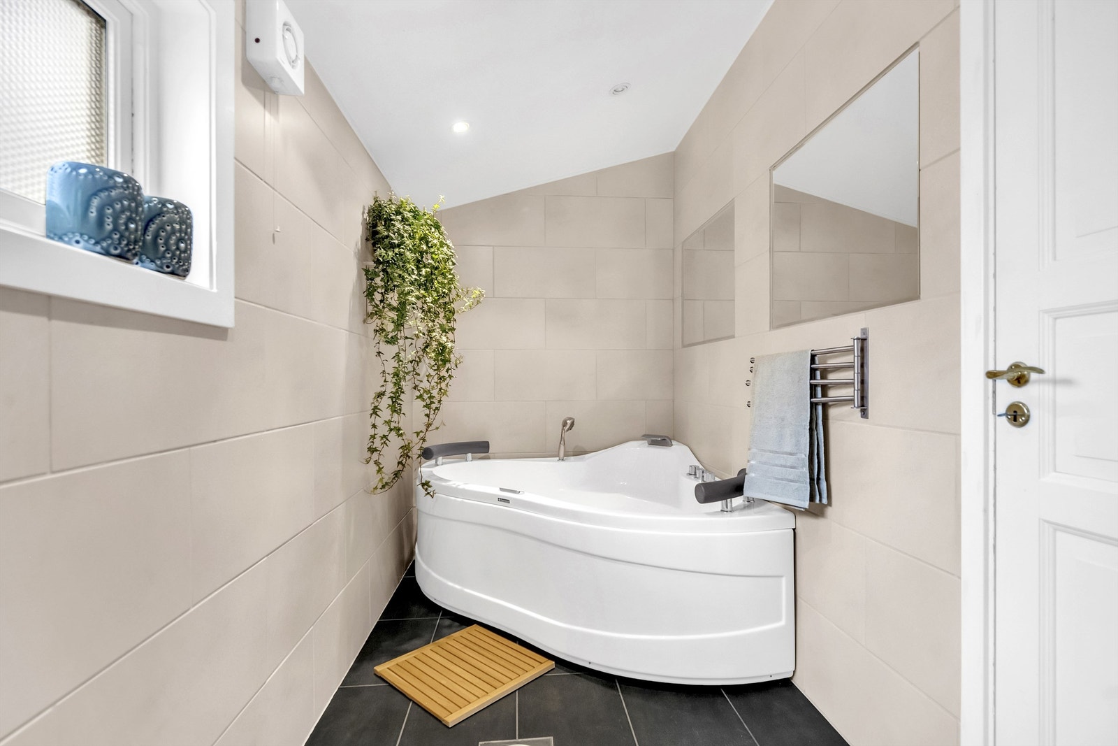 Pent baderom innredet med badekar, servantskap samt vegghengt toalett Galleribilde