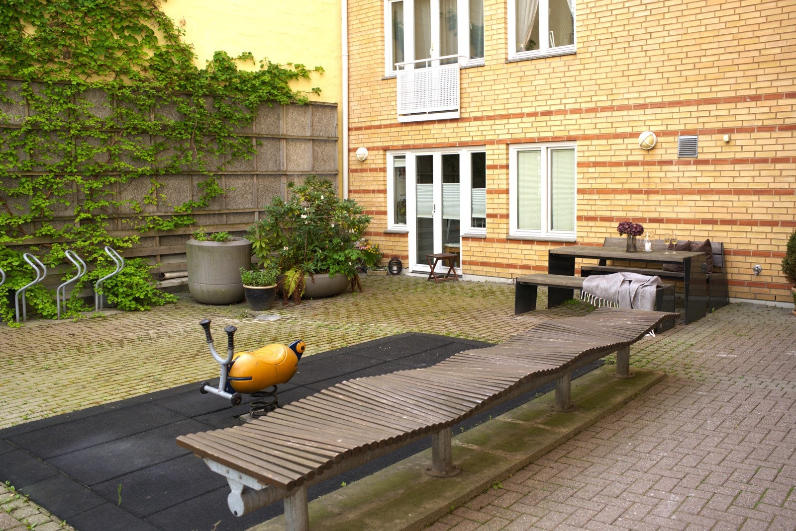 Det indre gårdsrommet er pent opparbeidet med heller og gjerder og pynte opp av klatreplanter på veggene, blomsterkasser med prydbusker og blomsterbed Galleribilde