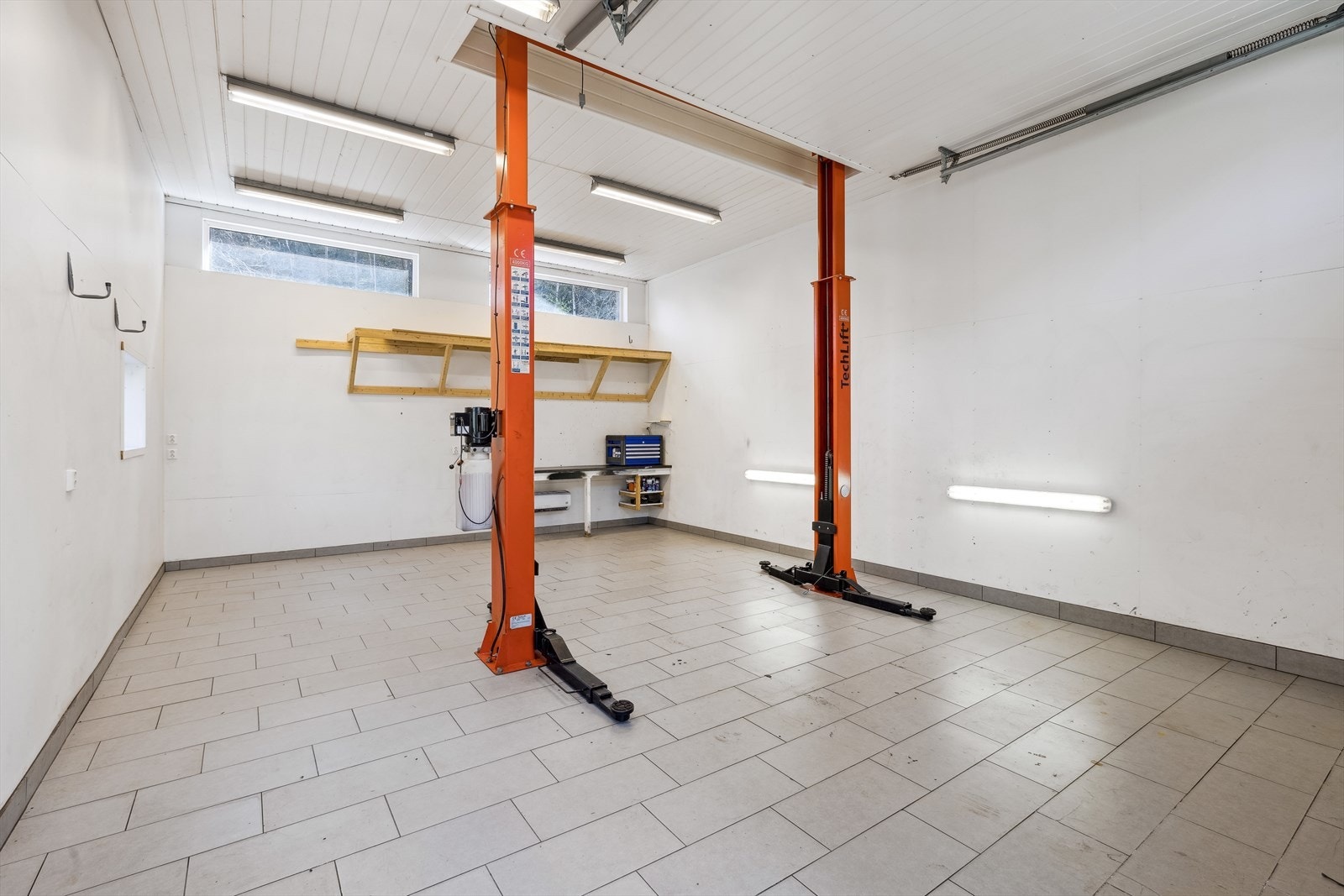 Fliselagt garasje med høyt til taket. Løftebukk følger med i salget Galleribilde