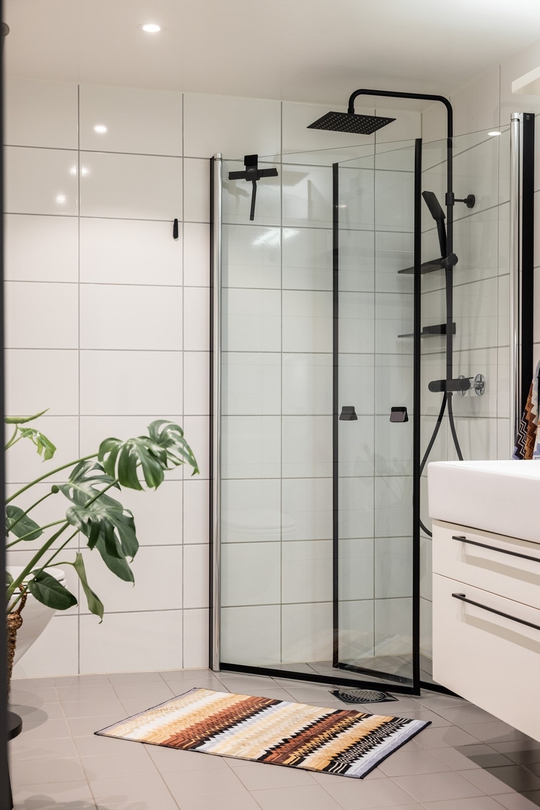 Badet er innredet med vegghengt klosett, servant på innredning og dusjhjørne med innfellbare glassdører. Galleribilde