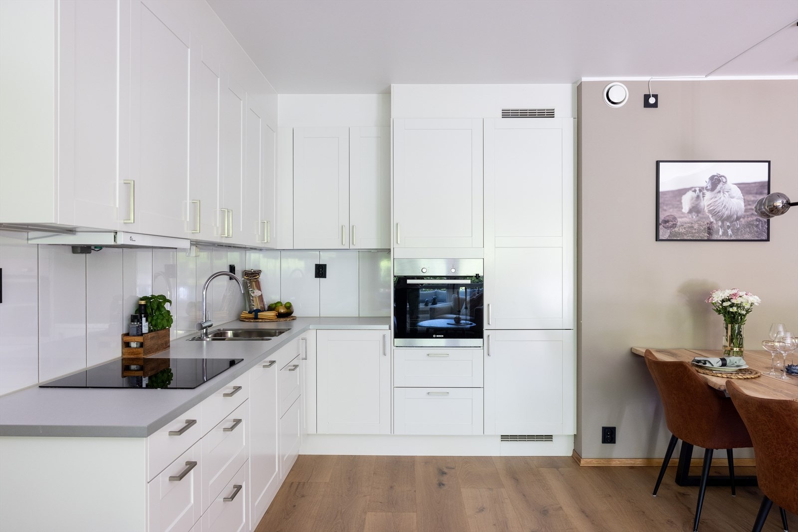 Kjøkkenet har et moderne preg og består av hvite, profilerte fronter og benkeplate av laminat med nedfelt vask. Galleribilde