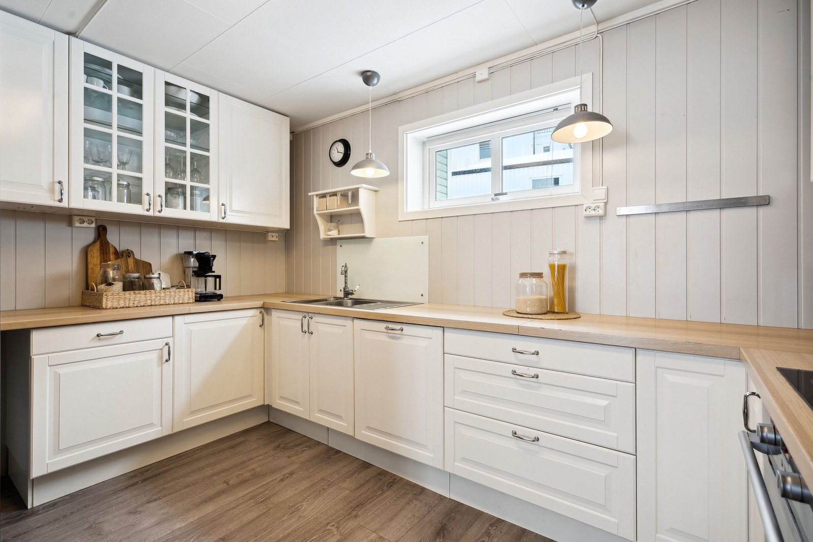 Kjøkkenet har innredning med profilerte fronter og laminat benkeplate, komfyr og integrert oppvaskmaskin Galleribilde