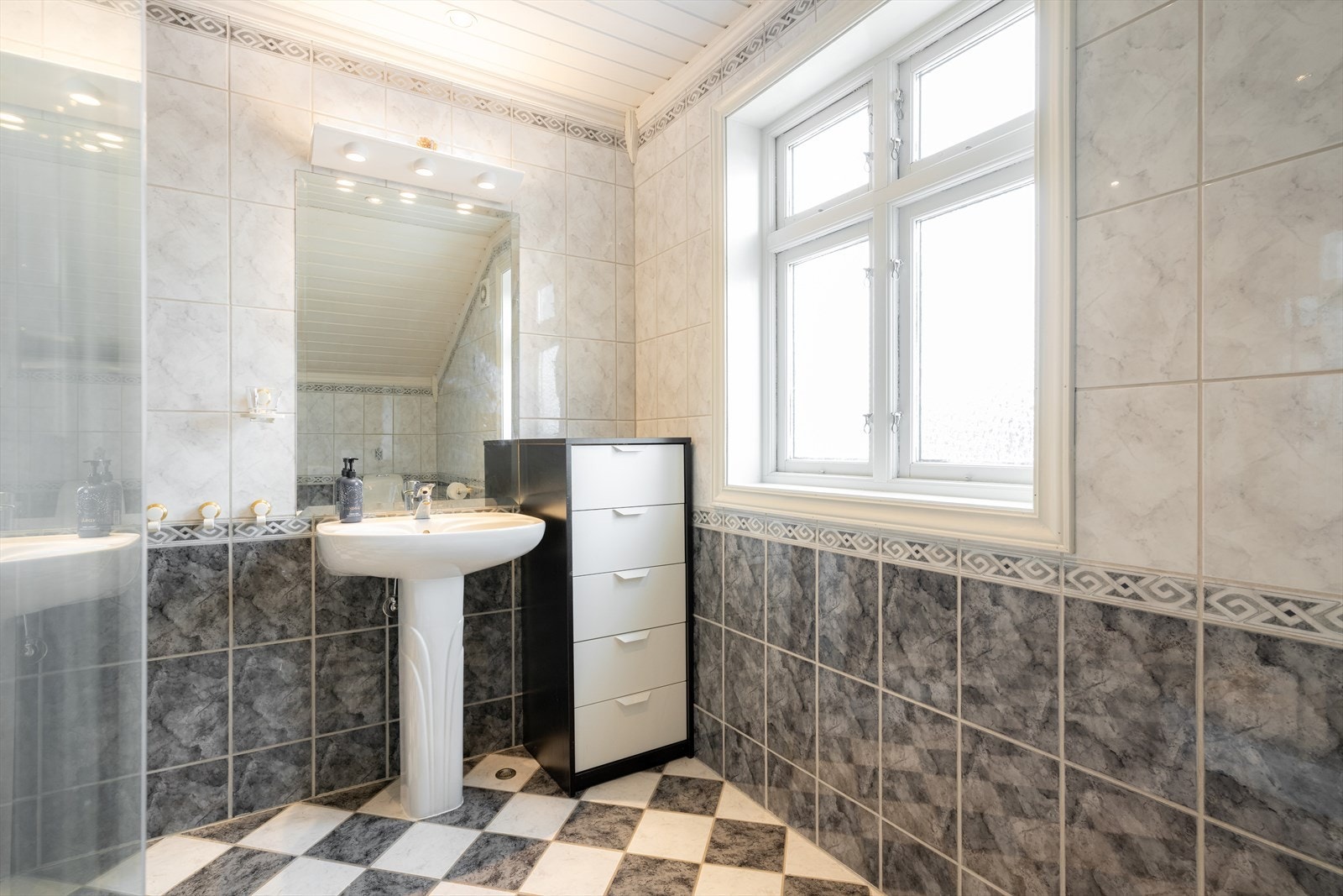 Bad med flis på gulv og vegger. Her er det søylevask, toalett og dusjkabinett, samt varmekabler i gulv og elektrisk styrt vifte i yttervegg. Galleribilde