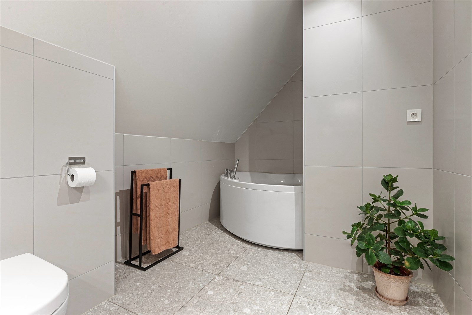 Badet er utstyrt med heldekkende servant med underskap, speil med lys, vegghengt toalett og frittstående badekar Galleribilde